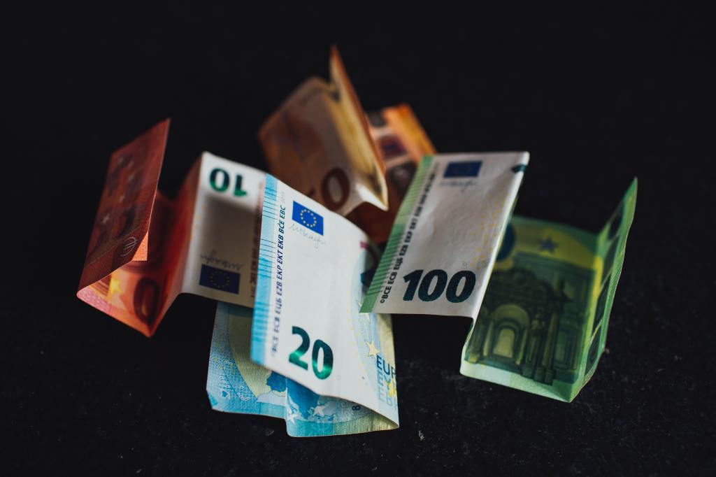 Mehrere fallende Euro-Geldscheine, fotografiert auf schwarzem Hintergrund.  